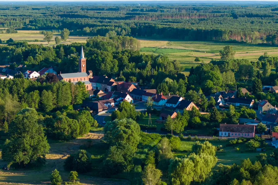 Zabudowa wsi z kościołem wśród pól, widok z lotu ptaka