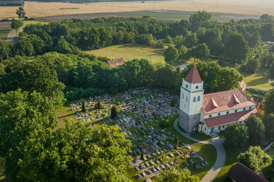 Kościół z cmentarzem wśród pól i lasów, widok z lotu ptaka